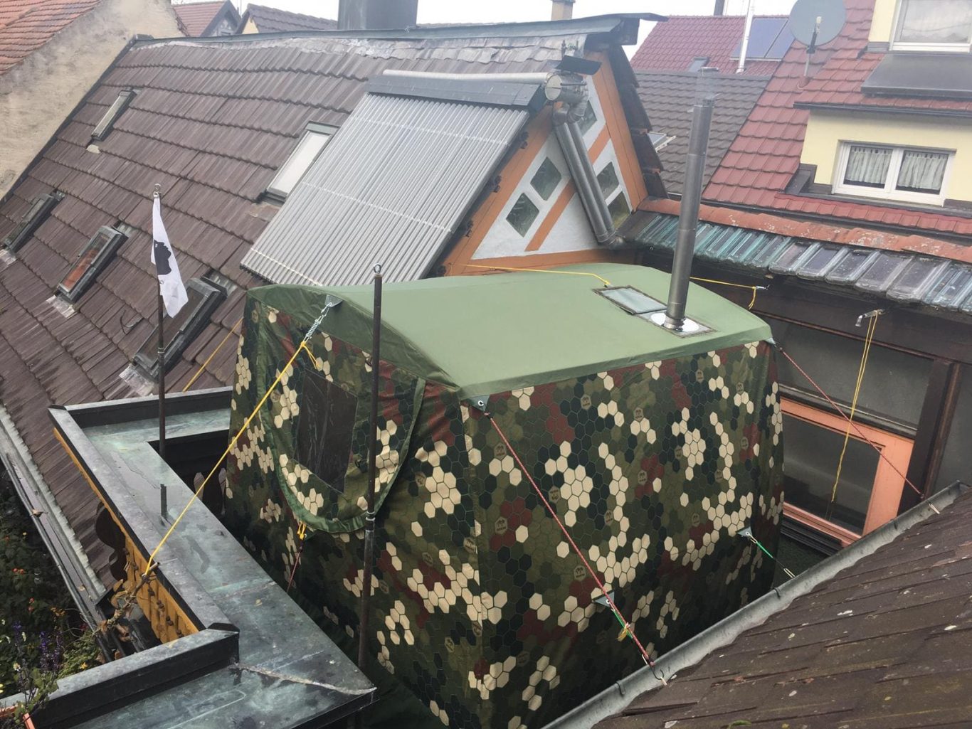 Mobiba MB-22 m³ auf der Dachterrasse Doppellagige Mobiba MB-22 m³ Zeltsauna in Wabenmusterung auf einer Dachterrasse zwischen Häuserdächern.